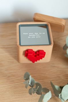 a small wooden box with a red heart on it and a message attached to the lid