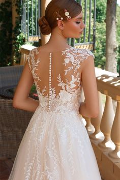 a woman in a wedding dress standing on a porch with her back to the camera