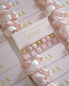 several pink boxes with gold foiled chocolates in them and ribbons tied around them