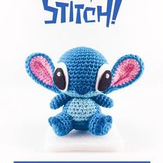 a small blue stuffed animal sitting on top of a white table next to a sign that says stitch