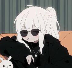 a person with white hair and sunglasses sitting on a couch next to a stuffed animal