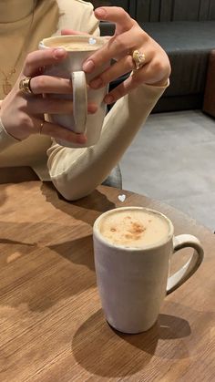 a woman sitting at a table with a cup of coffee