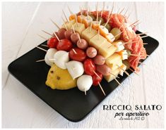 a black plate topped with meat and veggies on skewered toothpicks