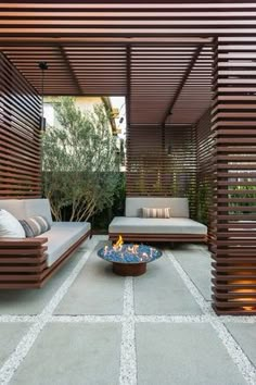 an outdoor living area with wooden slats and couches on the floor, in front of a fire pit