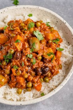 a white bowl filled with rice covered in meat and vegetables, garnished with cilantro