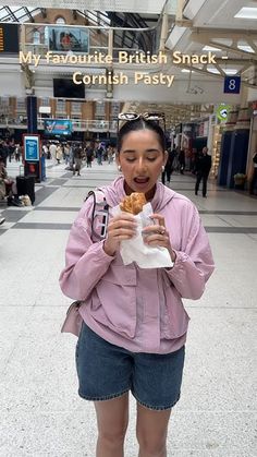 a woman standing in an airport holding food