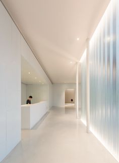 a long white hallway with a person sitting at the counter