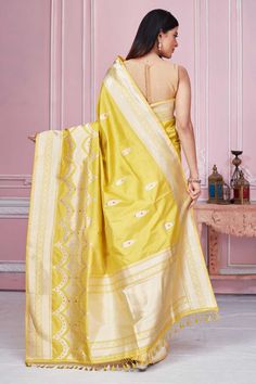 Radiate elegance on special occasions in this yellow Banarasi saree with zari border and zari minakari buta. It comes with a blouse piece. Disclaimer: The shown stitched blouse on the model is for display purpose only. The saree comes with a matching blouse piece and finished with fall and piko. Dola Silk Meenakari Blouse Piece, Yellow Saree With Cutdana Embroidery, Yellow Saree With Cutdana, Traditional Designer Yellow Blouse Piece, Traditional Yellow Designer Blouse Piece, Traditional Yellow Blouse Piece For Designer Wear, Gold Meenakari Tussar Silk Blouse Piece, Yellow Dola Silk Traditional Wear With Pallu, Chanderi Meenakari Blouse Piece