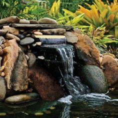 there is a small waterfall in the middle of some rocks and stones with water coming from it