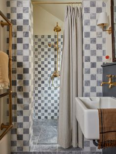 a bathroom with a checkered shower curtain next to a white sink and gold faucet