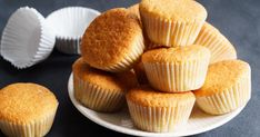 several muffins on a white plate next to some paper cupcake liners