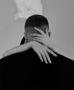 a man and woman embracing each other in black and white photo with hands covering their faces