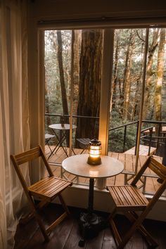 two chairs sitting at a table in front of a window with a candle on it