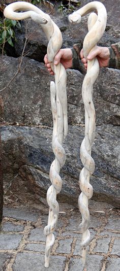 two large white objects are being held by someone's hands in front of some rocks