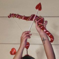 a woman holding up two hearts on a stick