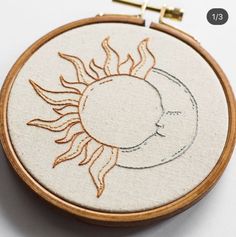 a sun and moon embroidered on a wooden hoop with stitching in the hoop around it