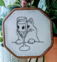 a hand embroidered picture of a cat holding a wine glass in it's mouth