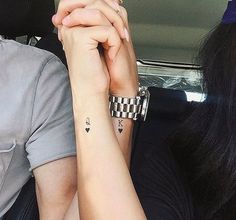 two people sitting next to each other in a car with tattoos on their arms and wrist