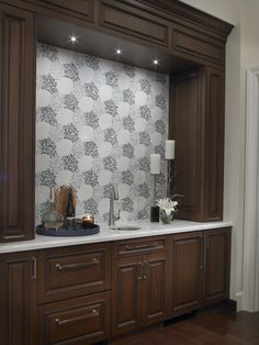 a kitchen with wooden cabinets and white counter tops, along with a wallpapered backsplash