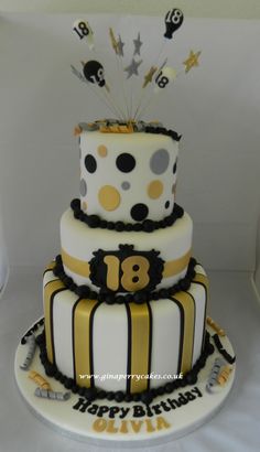 a three tiered birthday cake is decorated with black and white stripes, gold dots and stars