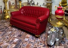 a red couch sitting on top of a floor next to a table with an elephant figurine