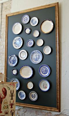 there are many blue and white plates on the wall next to an old card board