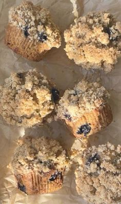 several blueberry muffins sitting on top of wax paper with crumbs