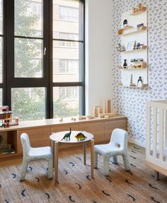 a baby's room with two chairs and a table in front of a window