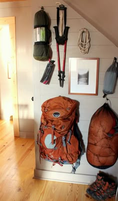 there are many backpacks hanging up on the wall in this room with wood flooring