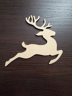 a wooden reindeer ornament sitting on top of a wood table next to a bottle opener