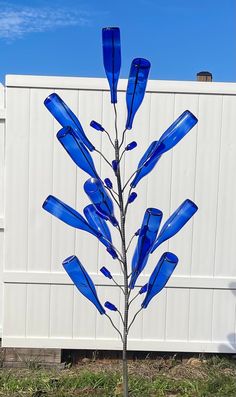 a blue glass tree in front of a white fence