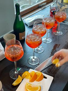 several glasses filled with different types of drinks on a table next to wine bottles and utensils