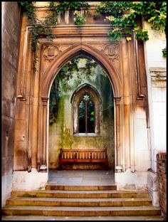 an old building with stairs leading up to it and a bench in the doorway that is covered by ivy