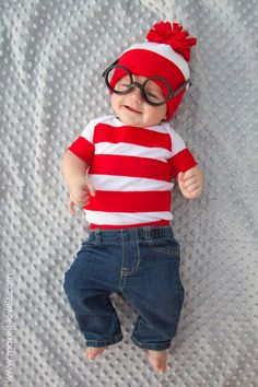 a baby wearing glasses and a red striped shirt is laying on a white bed sheet