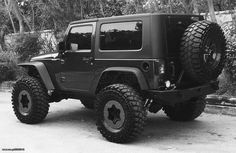 a black and white photo of a jeep with large tires on the front wheel drive