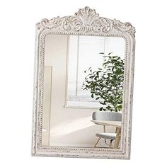 a white mirror sitting on top of a table next to a potted green plant