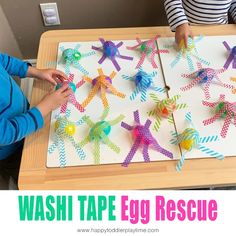 two children playing with wash tape egg rescue on a wooden table in front of a white board