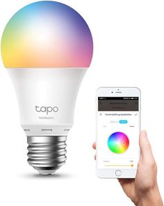 a person holding an iphone next to a smart light bulb with the app on it