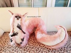 two pink and white stuffed animals sitting on top of a couch next to each other