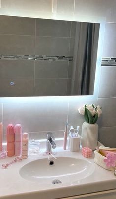 a bathroom sink with soap, lotion and other items on it in front of a large mirror