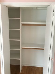 an empty closet with white shelves and wood floors