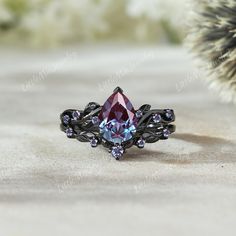 a ring with a blue and purple stone in it sitting on a table next to a cactus