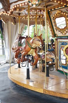 an old fashioned merry go round with animals on it's sides and lights hanging from the ceiling