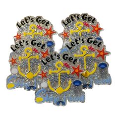 three metal badges with the words let's get lets get and an anchor on them