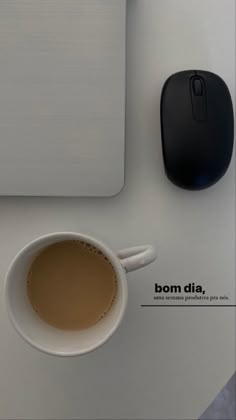 a cup of coffee sitting next to a computer mouse on top of a white desk