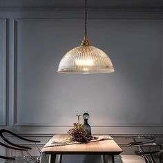 a dining room table with chairs and a light hanging over it's head on the wall