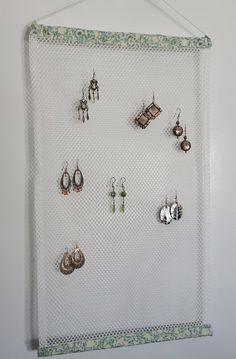 there is a white wall hanging with earrings and earring hooks on it, which are attached to the wall