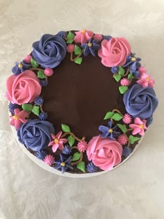 a chocolate cake decorated with pink and blue flowers on a white tableclothed surface