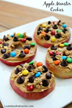 apples with candy and cereal on them sitting on a white plate