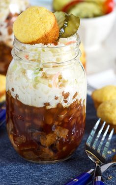 a jar filled with food sitting on top of a blue table cloth next to muffins